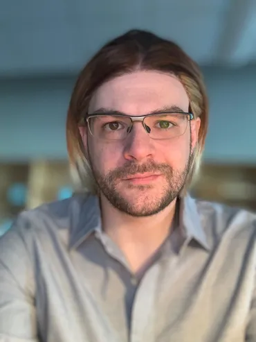 A man with long hair and glasses is wearing a shirt.