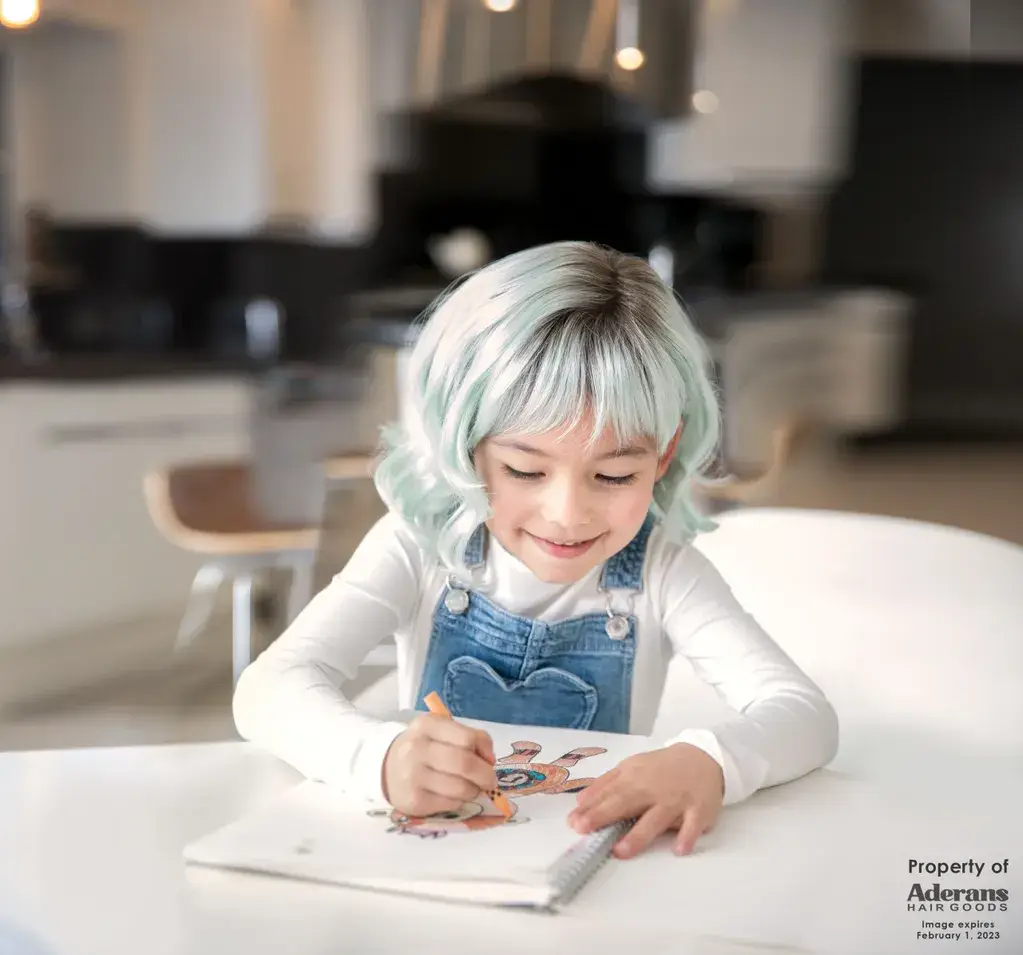 A child with blue hair writing on paper.