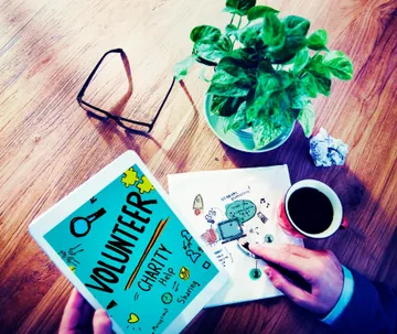 A person holding a book and cup of coffee.