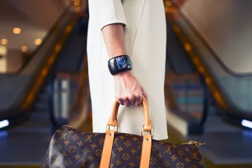 A woman holding onto her luggage with one hand.