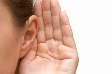 A person with their hand up to the side of his ear.