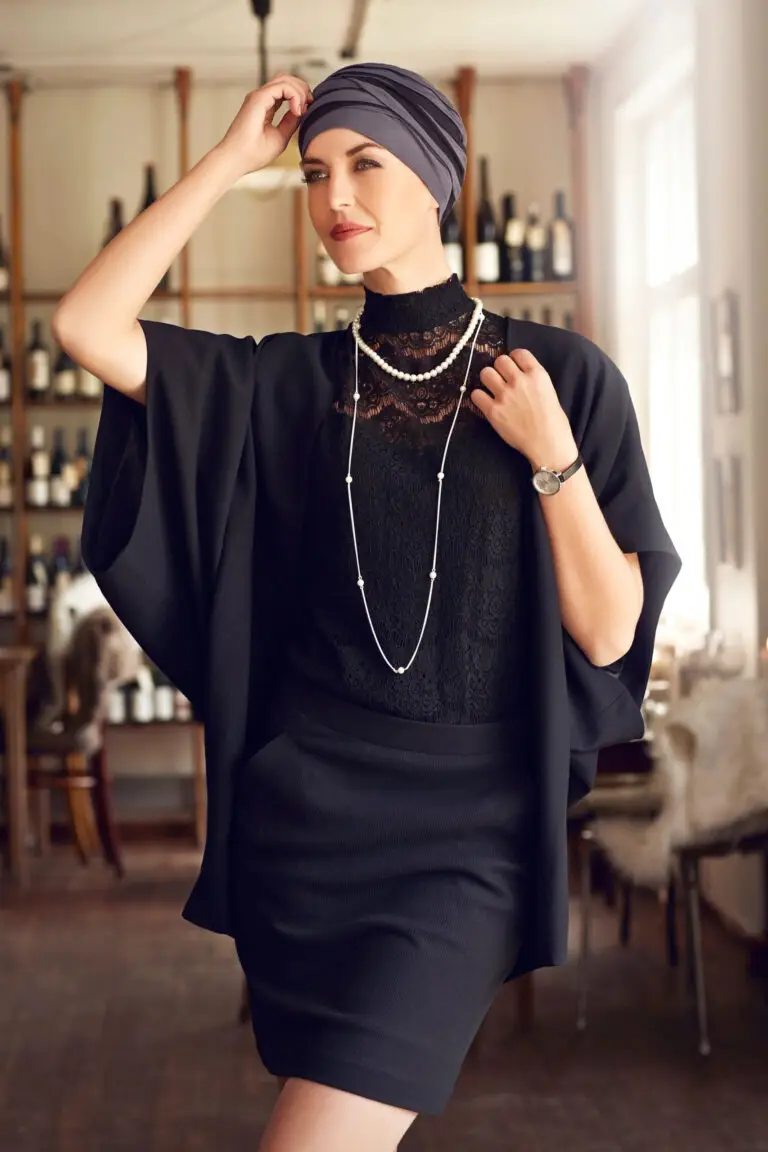 A woman in black dress standing next to wine bottles.