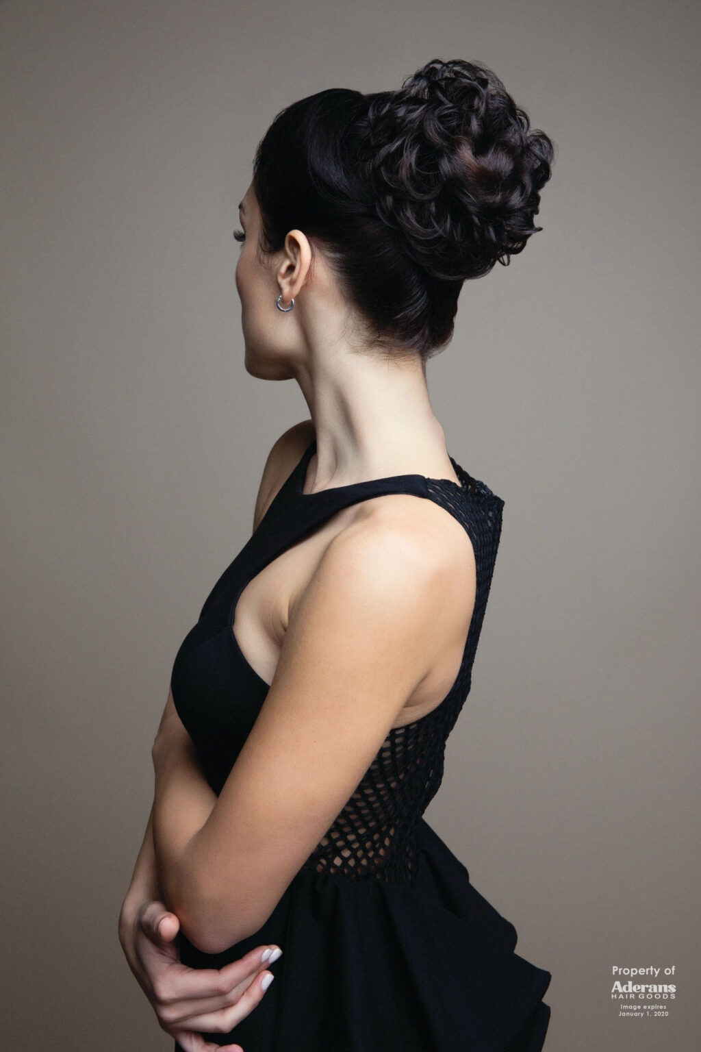 A woman with a black dress and a bun in her hair.