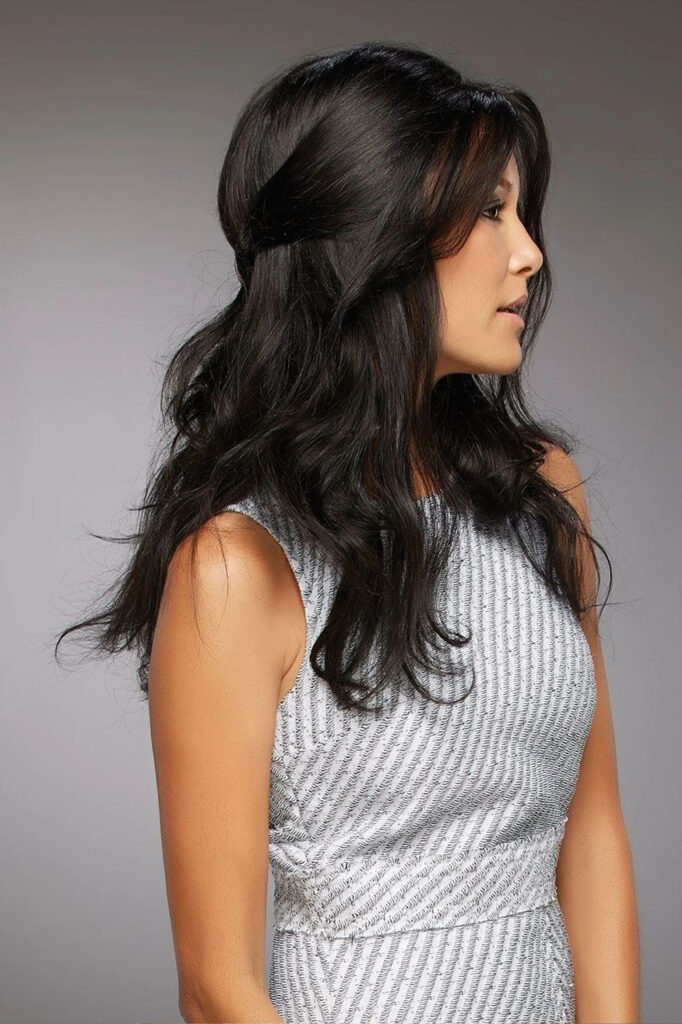 A woman with long black hair wearing a silver top.