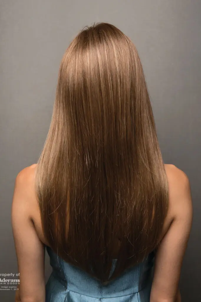 A woman with long hair is standing in front of the wall.