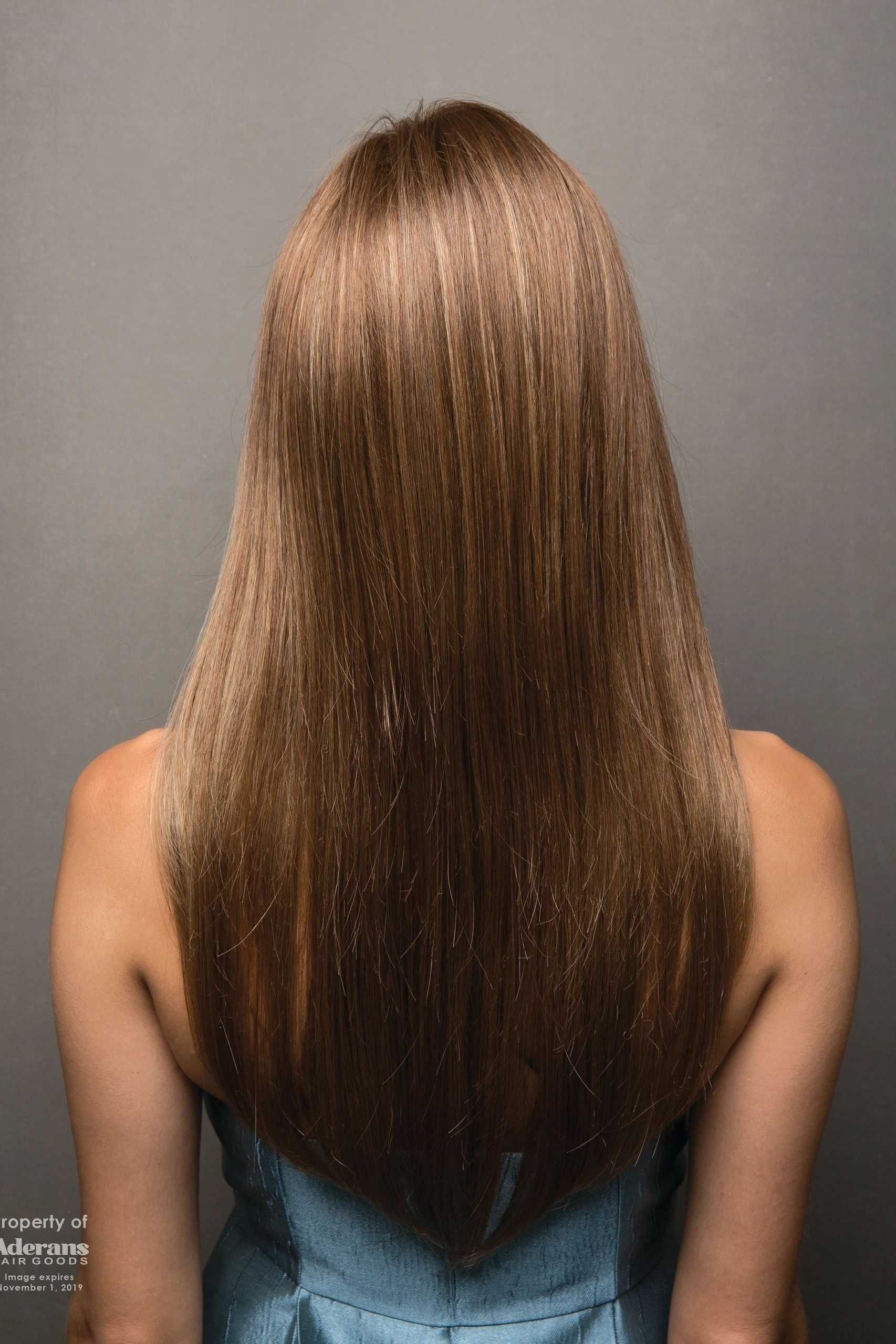 A woman with long hair is standing in front of the wall.